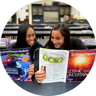 Two students reading scientific textbooks at a table.