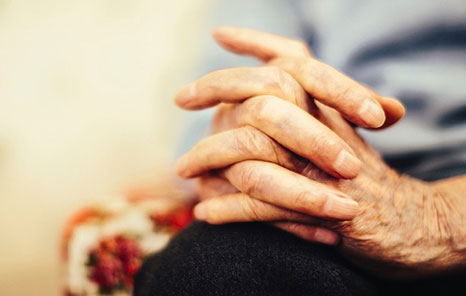  Close-up of an older adult’s hands clasped while seated, living with COPD