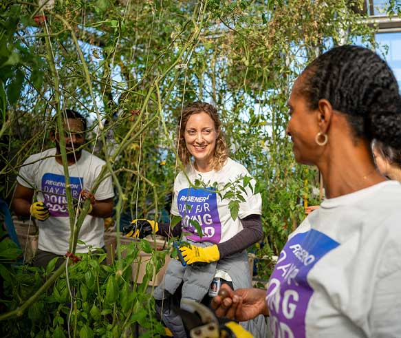 Regeneron employees smiling and working together on an outdoor community park cleanup project.