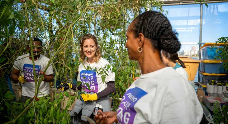Regeneron employees smiling and working together on an outdoor community park cleanup project.