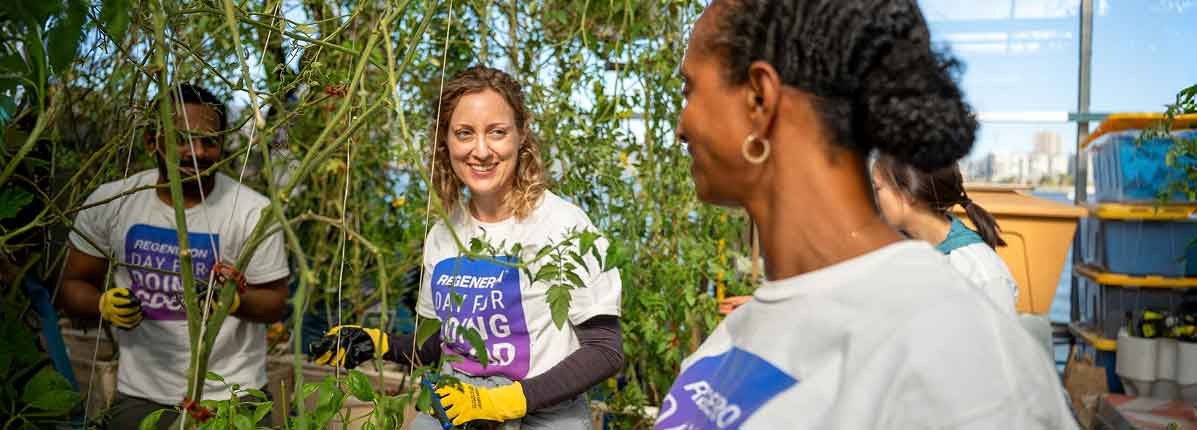 Regeneron employees smiling and working together on an outdoor community park cleanup project.