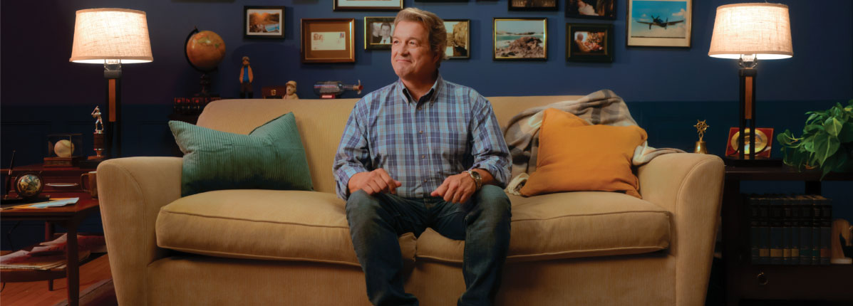 Hombre sentado en un sofá con fotos familiares en la pared