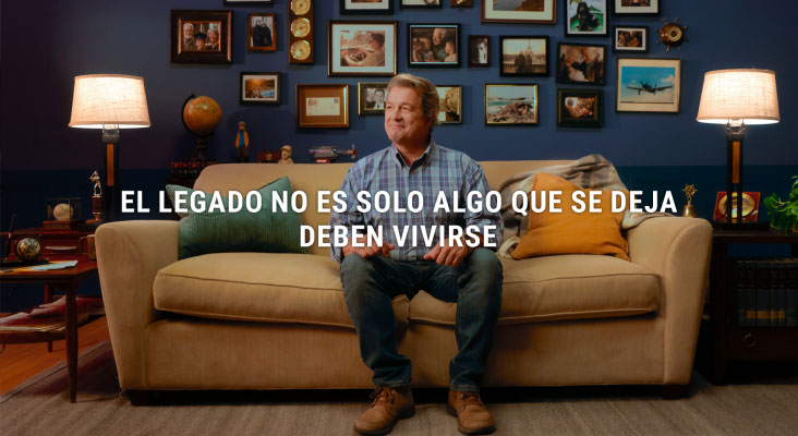 Hombre sentado en un sofá con fotos familiares en la pared